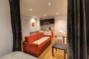 a living room with a red couch and a kitchen at Les Quais d'Annecy in Annecy