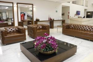 a lobby with leather couches and a table with purple flowers at Hotel Imperador in Gurupi