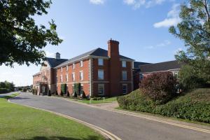 a large red brick building on a street at Whittlebury Hall and Spa in Whittlebury