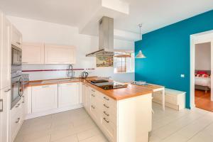 a kitchen with white cabinets and a blue wall at Villa Oasis by PriorityVillas in Palma de Mallorca