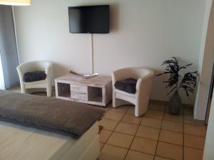 1 Schlafzimmer mit 2 Stühlen, einem Tisch und einem TV in der Unterkunft Gästehaus Lohmann in Bullay