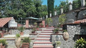 un jardín con una pared de piedra y escaleras con macetas en B&B Villa Teresa en Sorrento