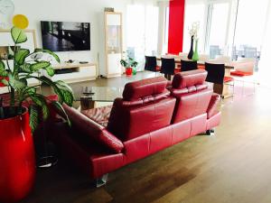 a living room with a red leather couch and chairs at Rhein Melodie riverview luxury in Konstanz
