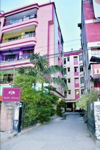 um edifício cor-de-rosa com uma palmeira à frente. em Atithi Ashray em Patna