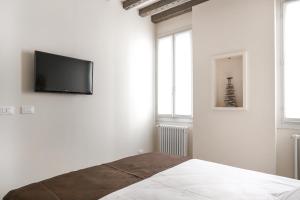 a white bedroom with a flat screen tv on the wall at Rialto Suite 1602 in Venice