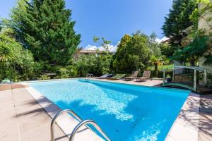 una grande piscina blu con sedie e alberi di Villa Trou Aux Biches a Oletta