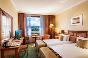 um quarto de hotel com duas camas e uma secretária em Danubius Hotel Helia em Budapeste