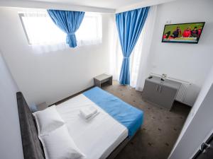 a small bedroom with a bed and blue curtains at Vila La Mer Mamaia Nord in Mamaia Nord