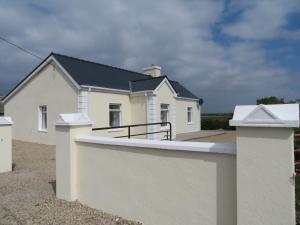a white house with a fence in front of it at Leam Cottage in Belmullet