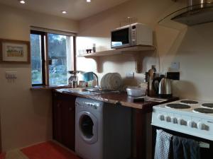 a kitchen with a stove and a washing machine at Sunrise House in Inverfarigaig