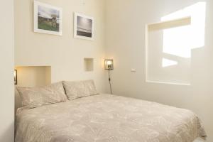 a white bedroom with a bed and two pictures on the wall at Iolanda Apartment 30m from Seaside in Alghero