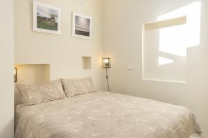 アルゲーロにあるIolanda Apartment 30m from Seasideの白いベッドルーム1室(ベッド1台付)、壁に2枚の絵画が備わります。
