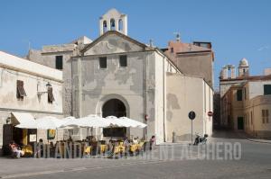 an old building with tables and umbrellas on a street at Iolanda Apartment 30m from Seaside in Alghero +15 photos