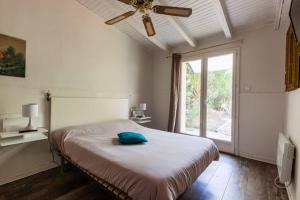 1 dormitorio con 1 cama, ventilador de techo y ventana en Villa Trou Aux Biches, en Oletta