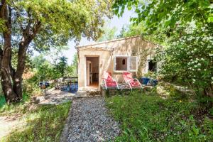 a small house with two red chairs in the yard at Villa Trou Aux Biches in Oletta
