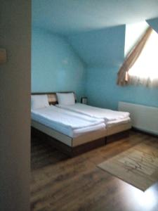een bed in een blauwe kamer met een raam bij Casa Toma in Sovata