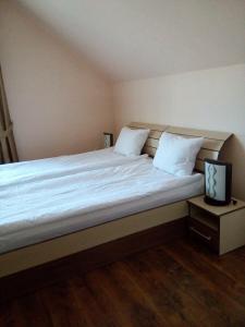 een slaapkamer met een groot bed met witte lakens bij Casa Toma in Sovata