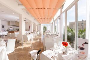 a restaurant with white tables and white chairs and windows at HSM Lago Park in Playa de Muro