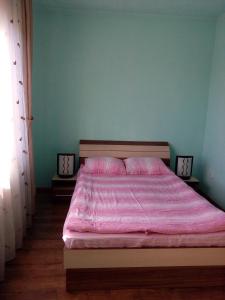 een slaapkamer met een bed met een roze dekbed bij Casa Toma in Sovata