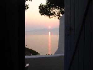 a view of the ocean from a door with the sunset at Rosys Little Village in Skala