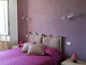 um quarto roxo com uma cama com lençóis e almofadas roxos em B&B La Costa em Pignone