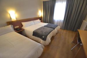 a hotel room with two beds and a window at Hotel Brujas De Irues in Tarazona de Aragón