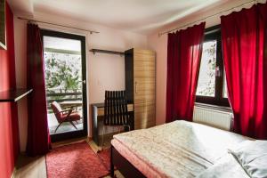 a bedroom with red curtains and a bed and a chair at Apartments Cortina in Zlatibor