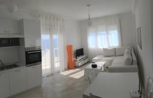 ein weißes Wohnzimmer mit einem Sofa und einer Küche in der Unterkunft White Residence Apartament in Sarandë