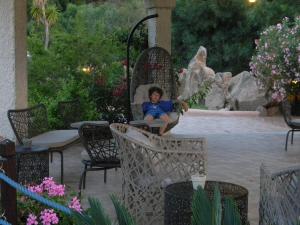 a woman sitting in a chair in a garden at Relais Fenicottero Rosa in Porto San Paolo