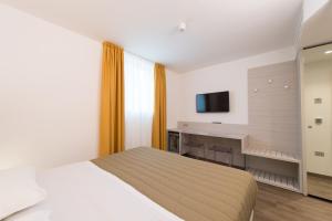 a bedroom with a bed and a desk and a television at Grand Hotel Liberty in Riva del Garda