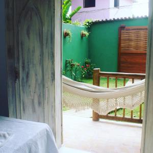 een veranda met een hangmat en een groene muur bij Pousada Amor de Casa in Trancoso