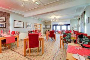 a dining room with tables and red chairs at Number One South Beach in Blackpool