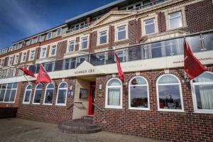 Um edifício de tijolos com bandeiras vermelhas à frente. em Number One South Beach em Blackpool