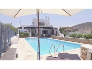 a swimming pool with an umbrella in front of a house at Villa Blue Island in Artemida