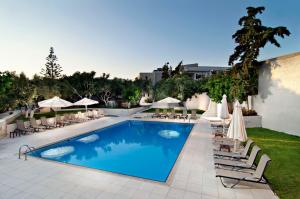 a swimming pool with lounge chairs and umbrellas at Ourania Apartments Hotel in Gouves