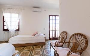 1 Schlafzimmer mit 2 Betten, Stühlen und Fenstern in der Unterkunft Spazioso Appartamento al Mare con Giardino in Capoterra