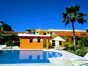 a pool in front of a house with a palm tree at Hotel Porto Garden in Porto Seguro