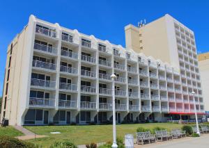 a large white building with chairs in front of it at Ocean Sands Resort, Oceanfront, Virginia Beach by Vacatia in Virginia Beach