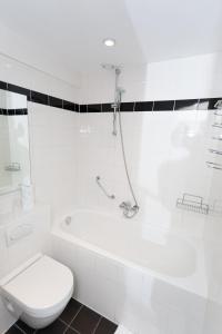 a white bathroom with a toilet and a bath tub at Hotel Park Plantage in Amsterdam