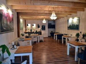 een restaurant met houten vloeren en tafels en stoelen bij Pension am Birkensee in Detern