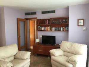 - un salon avec deux chaises blanches et une télévision dans l'établissement Atico de Víctor, à L'Ametlla de Mar