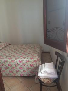 ein Schlafzimmer mit einem Bett, einem Stuhl und einem Spiegel in der Unterkunft Bixio Apartments in San Vito lo Capo