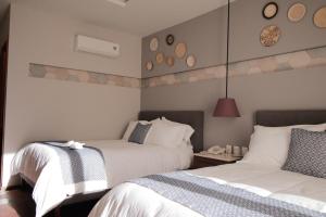2 Betten in einem Hotelzimmer mit Uhren an der Wand in der Unterkunft Casa Rosa Gran Hotel Boutique in Puebla
