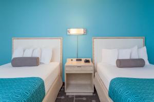 two beds in a hotel room with blue walls at Howard Johnson by Wyndham Mystic in Mystic