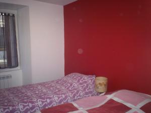 een slaapkamer met een bed en een rode muur bij L'Espaviot aux portes du Puy en Velay in Espaly-Saint-Marcel