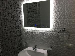 ein Badezimmer mit einem weißen Waschbecken und einem Spiegel in der Unterkunft White Residence Apartament in Sarandë