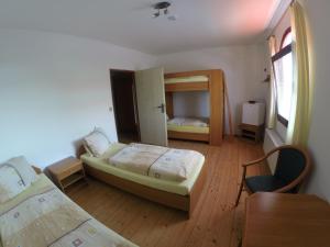 Cette chambre comprend deux lits, un bureau et une table. dans l'établissement Penzion Jaroš, à Popůvky