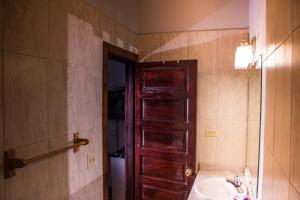 a bathroom with a wooden door and a sink at Serenade Hotel in Placencia Village +37 photos