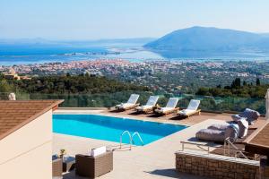 a pool with lounge chairs and a view of a city at Alivia Lefkas Luxury Villas in Apolpaina
