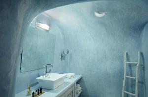 Baño azul con lavabo y espejo en Naftilos Houses, en Oia